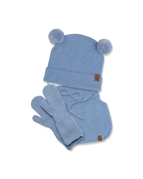A flat lay of a light blue knit winter set, consisting of a beanie with two pom-poms on top and a brown tag, a neck warmer with a brown tag, and a pair of mittens, all against a white background.