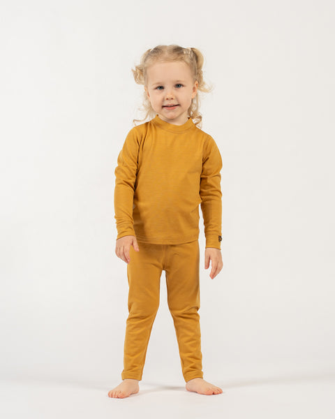 Child wearing a menique merino wool kids' yellow outfit on a white background