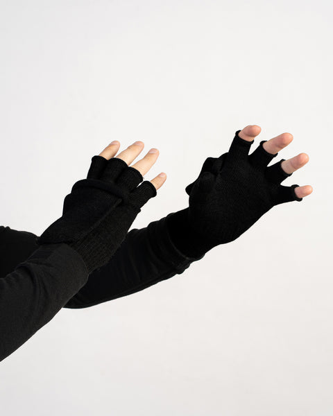 Black merino wool convertible gloves shown open as fingerless mitts, hands raised on white background.