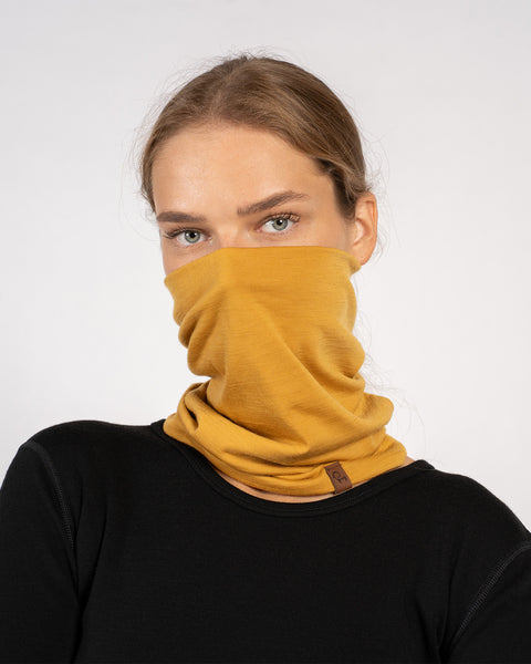 Yellow Merino wool neck gaiter pulled up over mouth and nose, woman in black top.