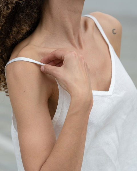 Beautiful woman posing in a city. Wearing pure white linen slip top.