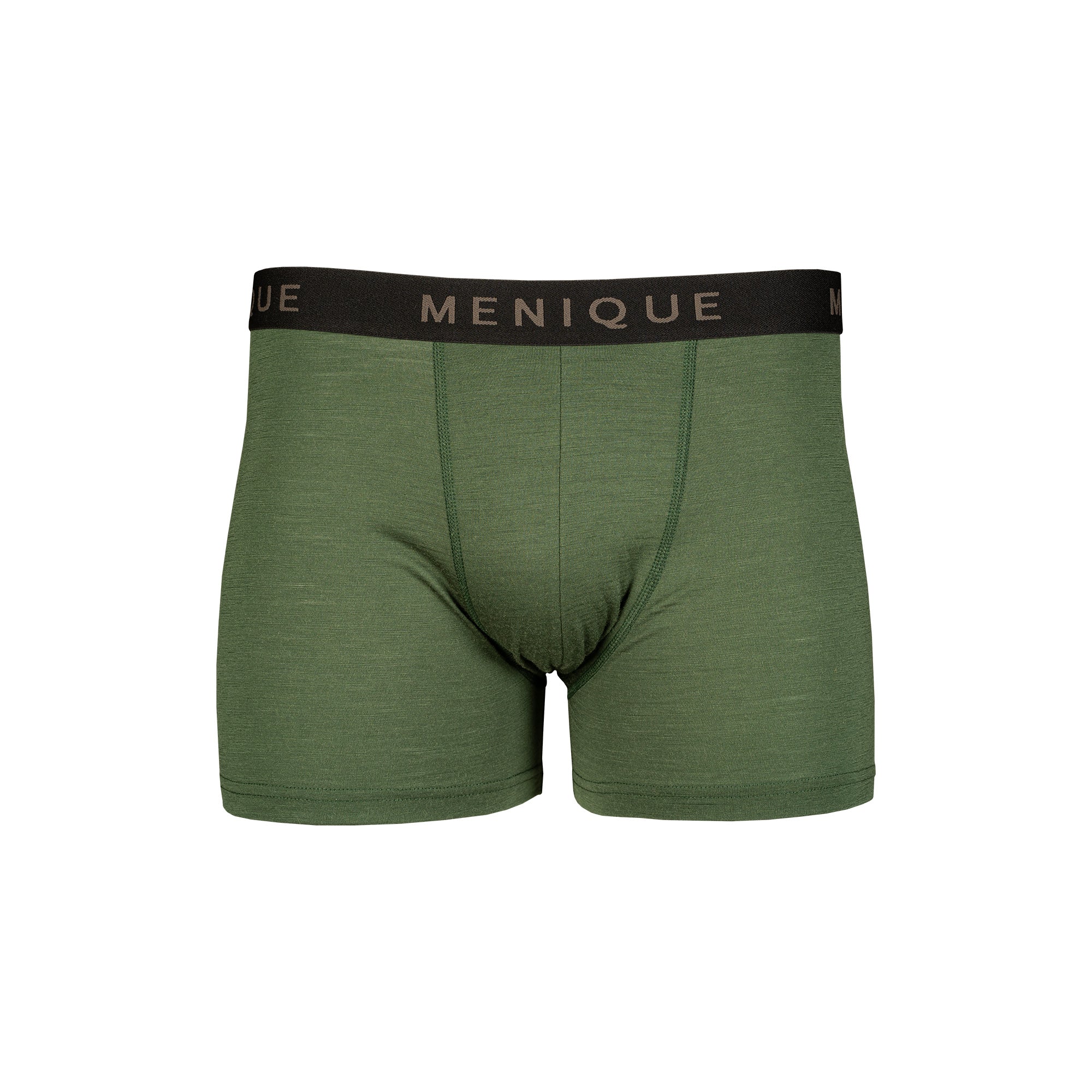 Man relaxing on a bed wearing dark green MENIQUE boxer briefs and a white T-shirt in a softly lit bedroom.