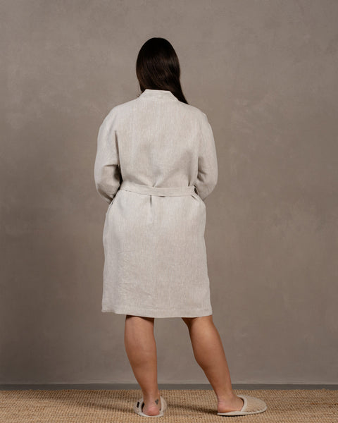 The menique women&#39;s linen bathrobe in natural color. The woman is showing the back of the bathrobe in size L-XL