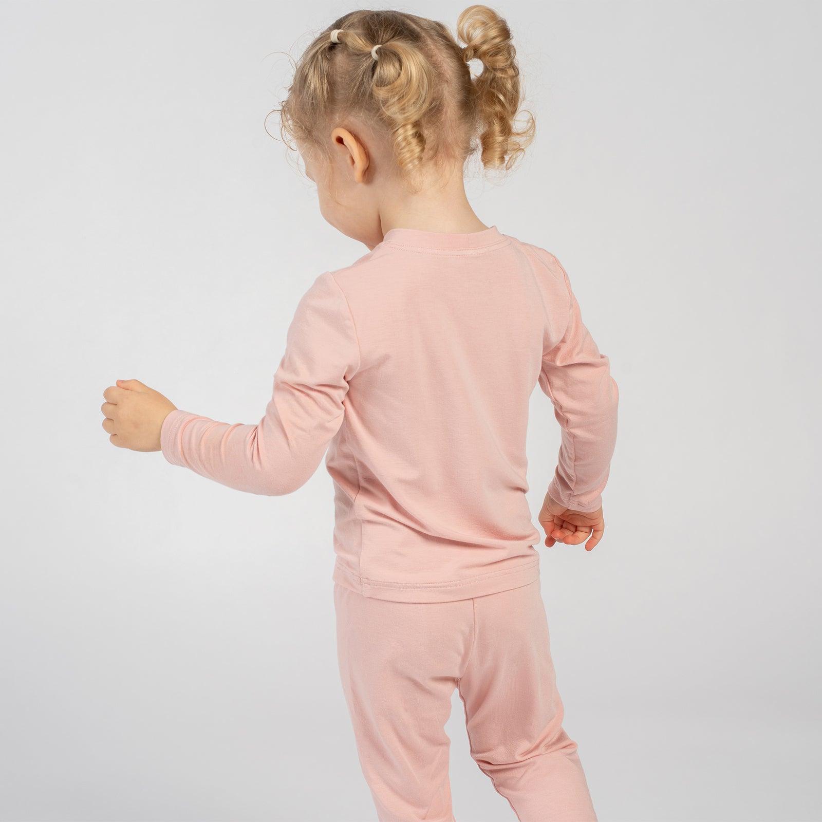 Side view of child in pink bamboo long-sleeve top and bottoms.