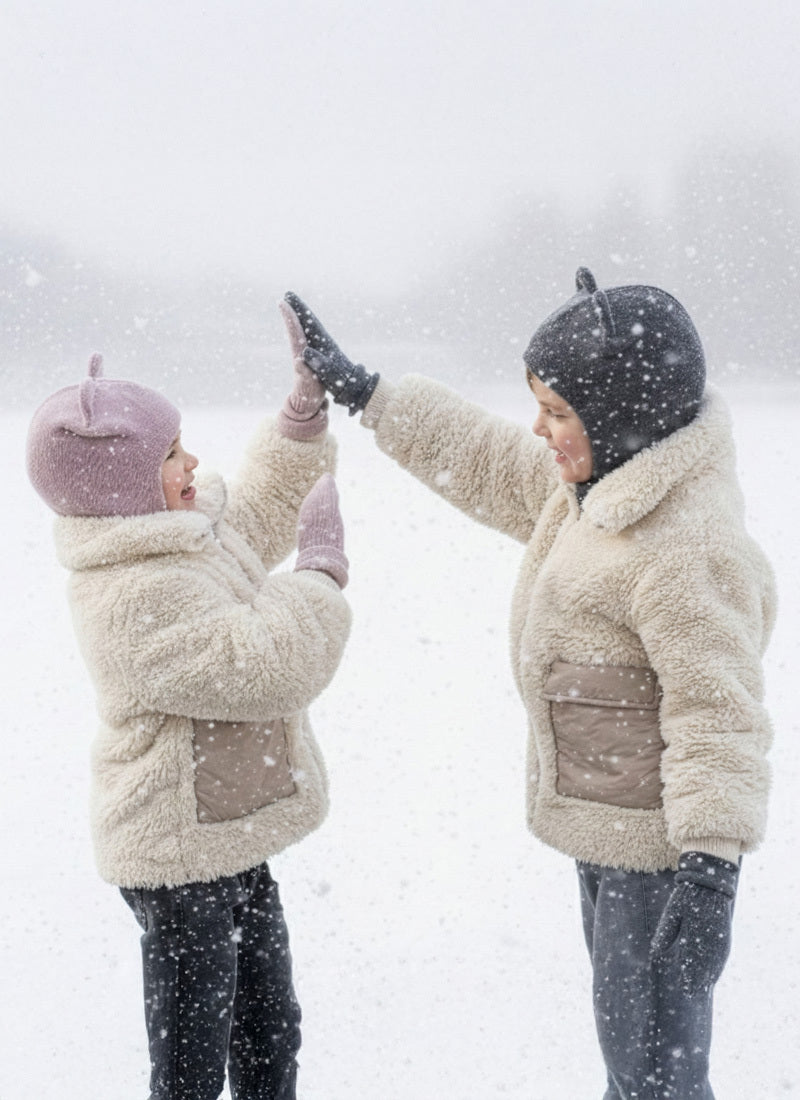 Two people in winter clothing giving each other a high-five in a snowy scene.