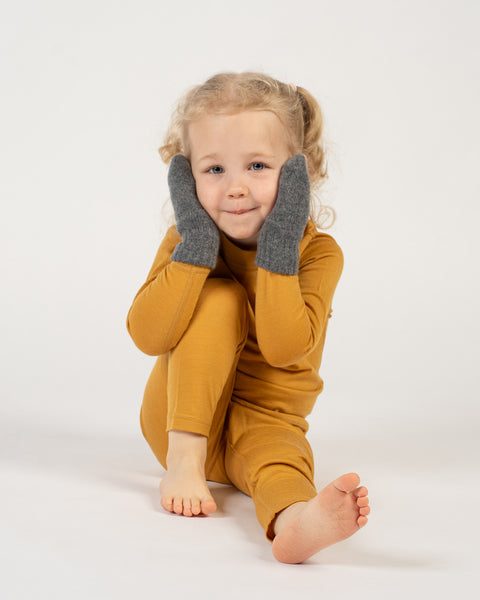 Child wearing spicy yellow merino set with dark gray menique gloves on a white background