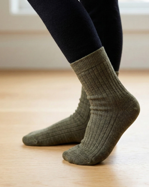 Person wearing ribbed merino wool socks standing on wooden floor.