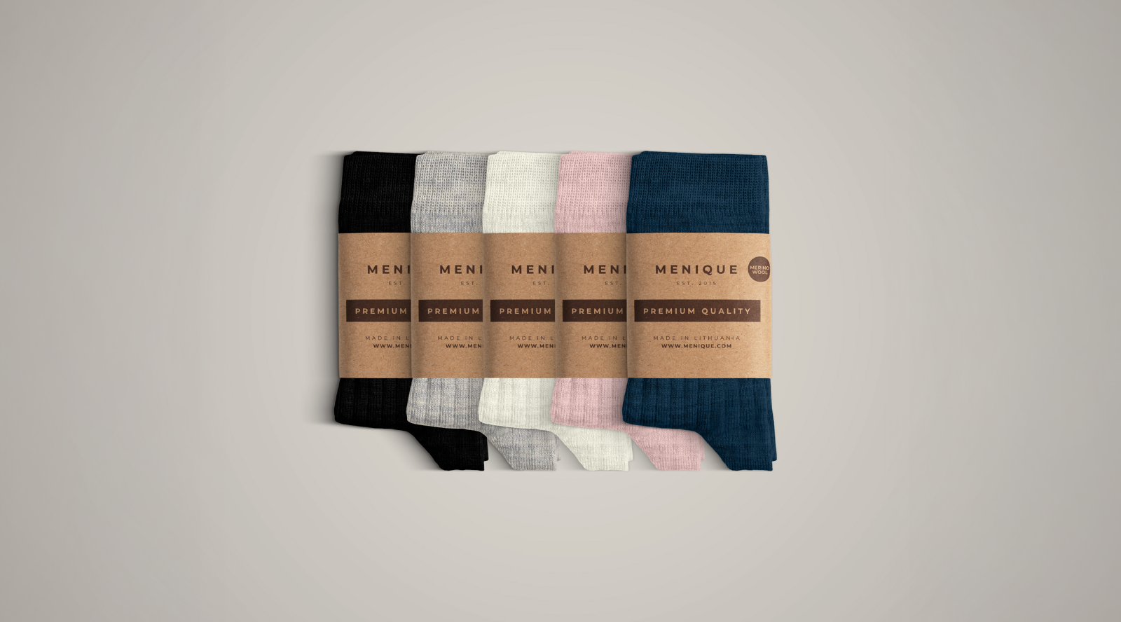 A neat stack of five pairs of ribbed knit socks displayed against a plain background. From left to right, the colors are black, light grey, cream, light pink, and navy blue. Each pair is wrapped with a brown cardboard label bearing the brand name "MENIQUE" and the words "PREMIUM QUALITY".