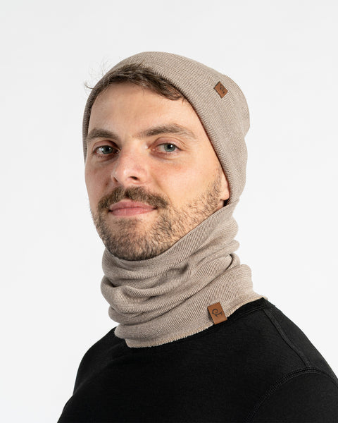 Man wearing a creamy beige merino wool knit beanie and scarf set on a white background
