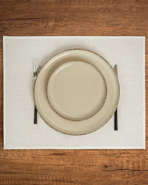 The menique linen placemat in pure white color on a wooden table top. 