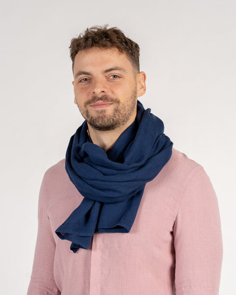 Man wearing a blue scarf and pink shirt against a white background