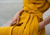 Close-up of a woman’s waist wearing a mustard yellow linen dress from menique, tied with a matching fabric belt, with hands resting in the dress pockets.