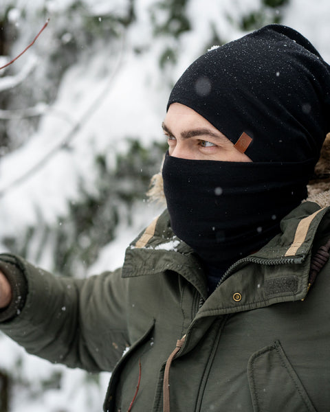 Menique Men&#39;s Merino Beanie and Gaiter Accessory Set worn by a man, in winter time. The set is in black color.