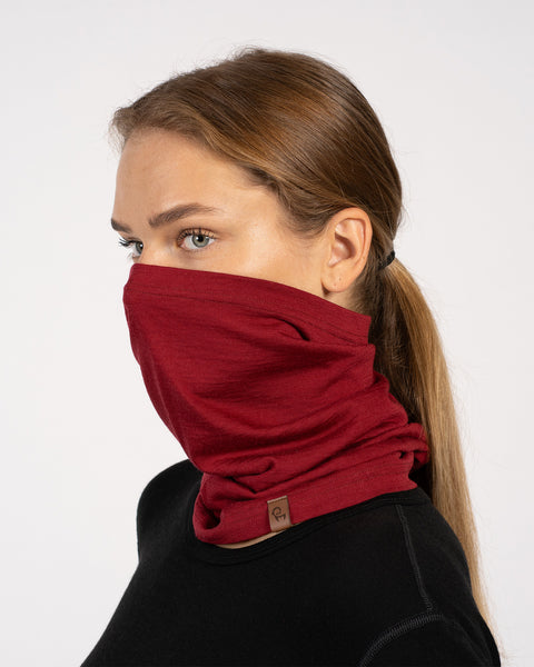 Side view of a woman wearing a royal cherry red Merino wool neck gaiter covering her nose and mouth.