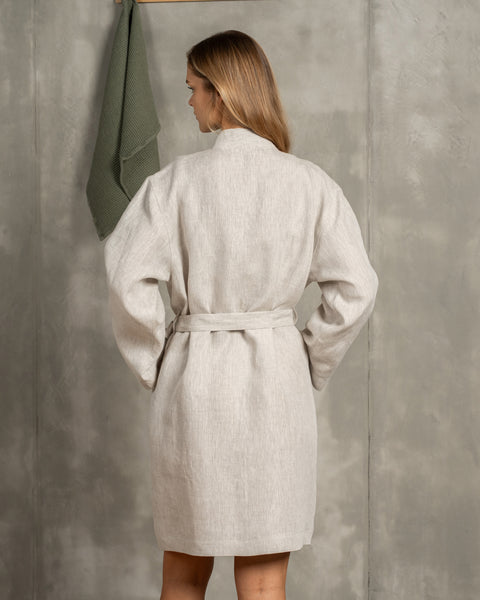 The menique women&#39;s linen bathrobe in natural color. The woman is showing the back of the bathrobe.