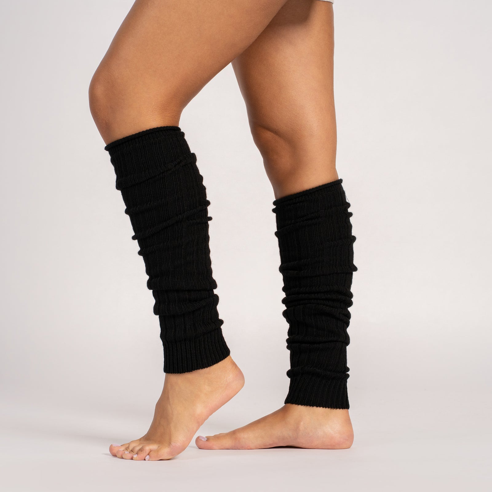 Black leg warmers worn by a person on a white background
