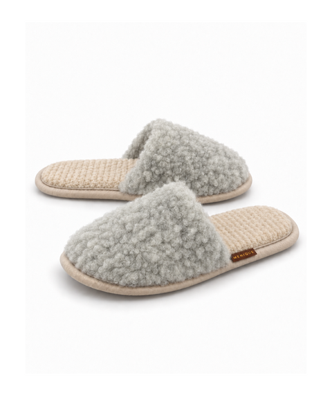 A pair of gray, fuzzy, slip-on style slippers with a matching textured footbed and a small brown "MENIQUE" tag.