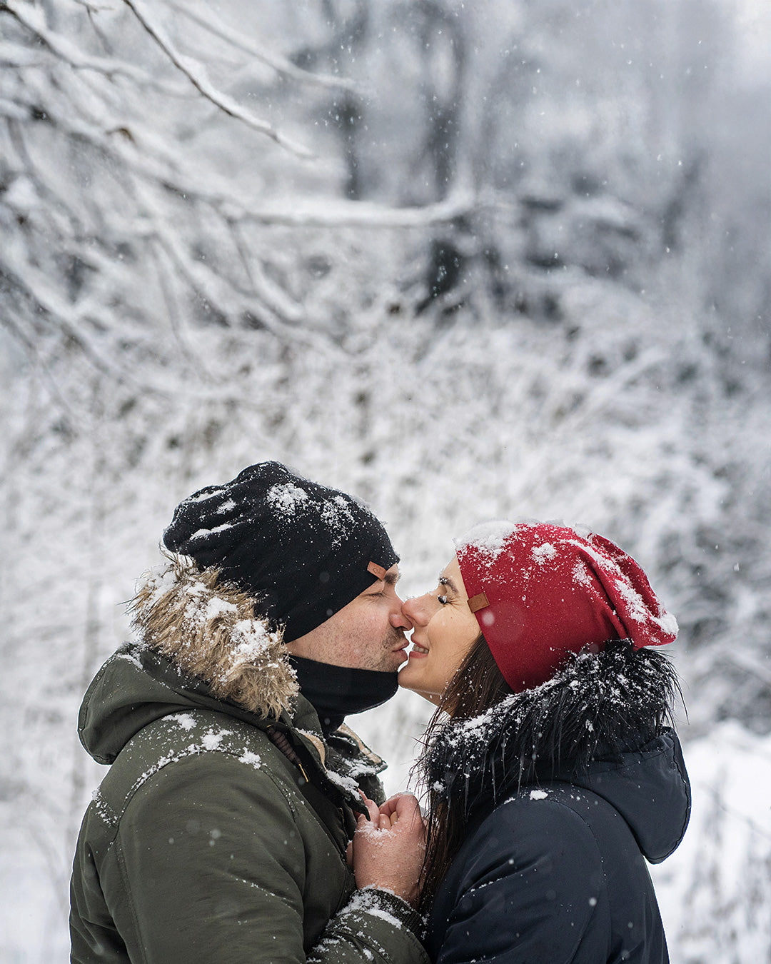 Couple wearing Merino wool beanies sharing a moment outdoors in snowy winter landscape