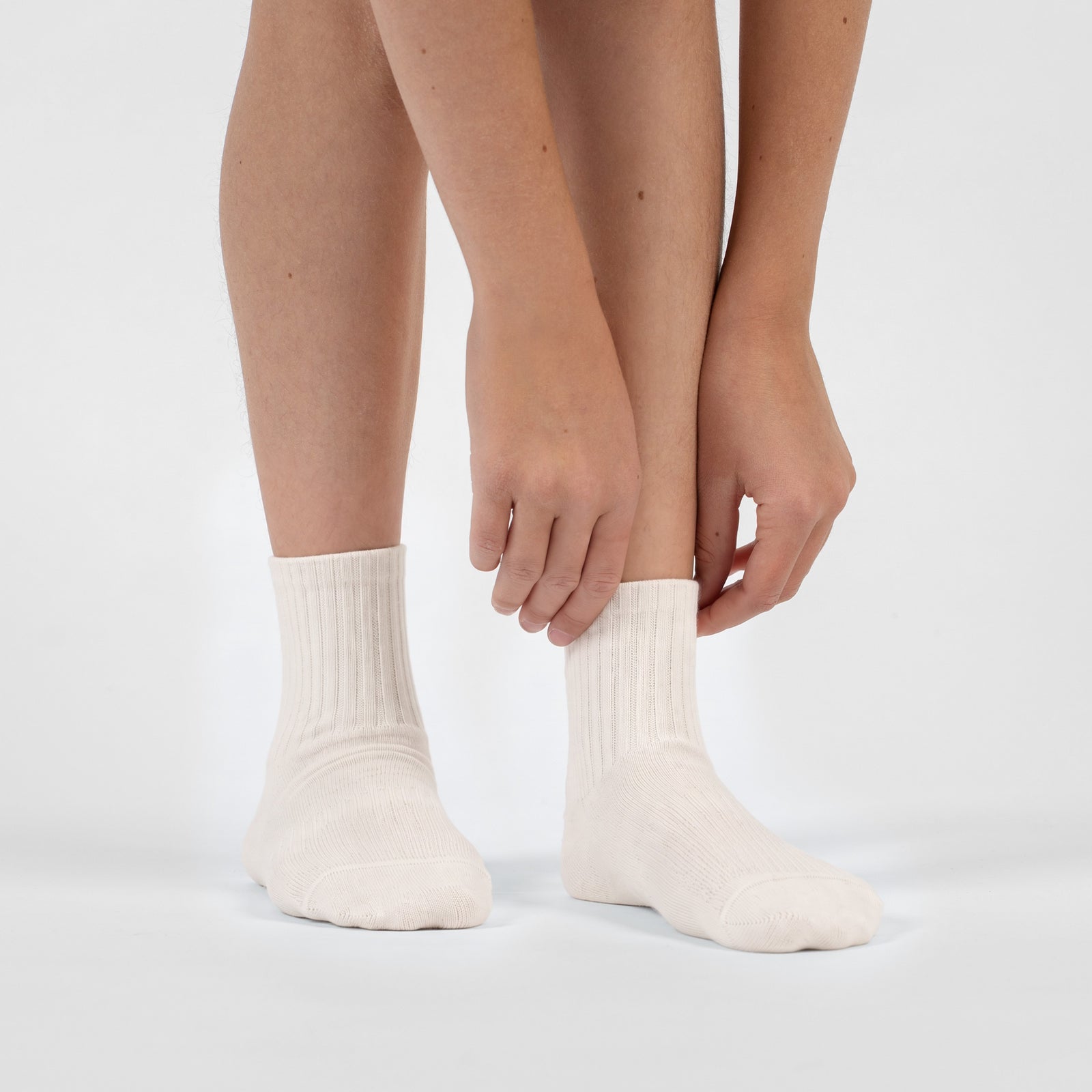 A pair of natural off-white, ribbed crew socks lying flat against a plain white background.