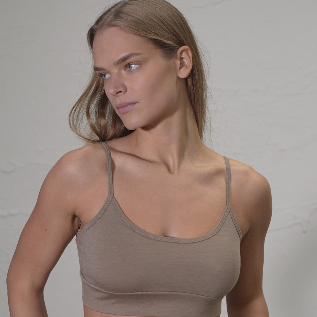 Model wearing 100% Merino Wool Beige color bralette, turning slightly and looking to the side in a studio setting. 
