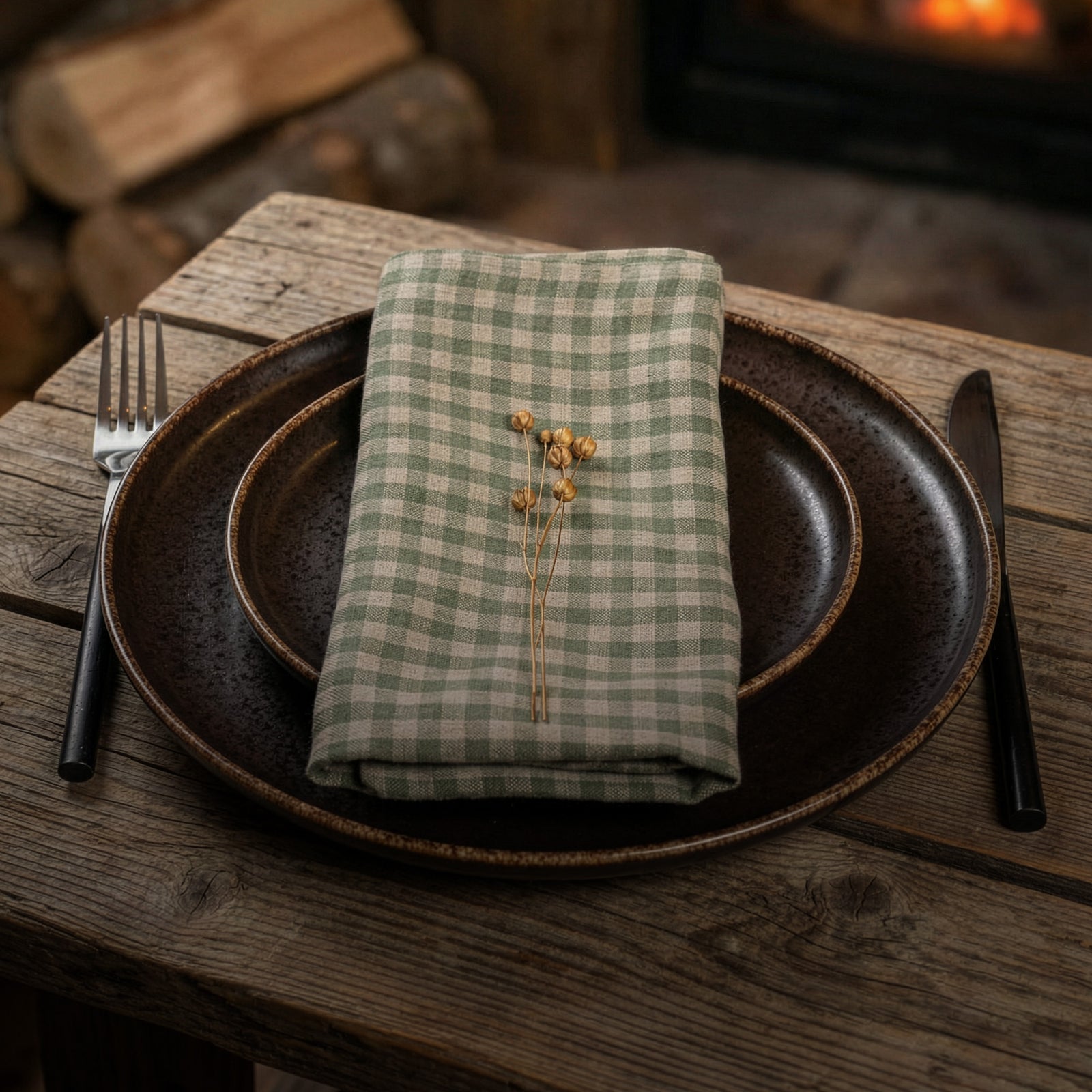 Set table with checkered napkin, plates, fork, and knife on a wooden surface.